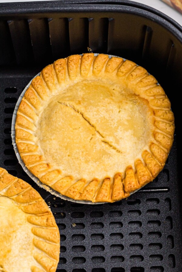 Golden pot pies in an air fryer basket after being cooked