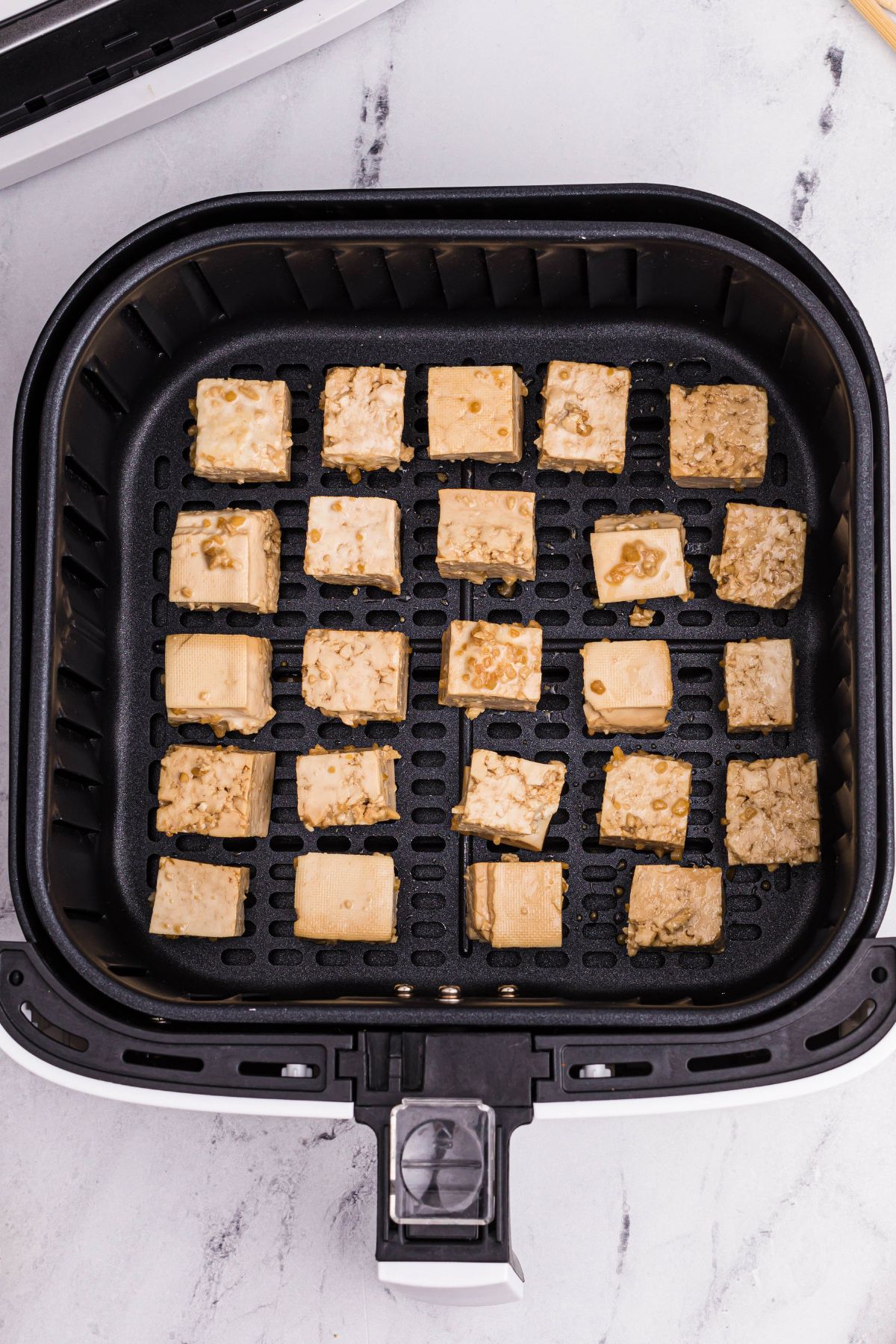 tofu cubes in the air fryer basket before being cooked until crispy