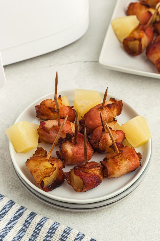 Crispy bacon wrapped pineapple chunks on a small white plate 