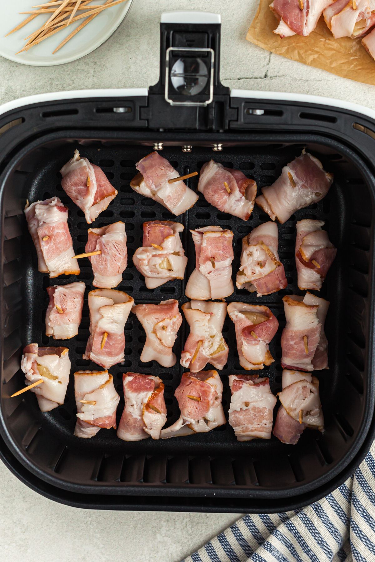 Bacon wrapped pineapple bites in the air fryer basket before being air fried.