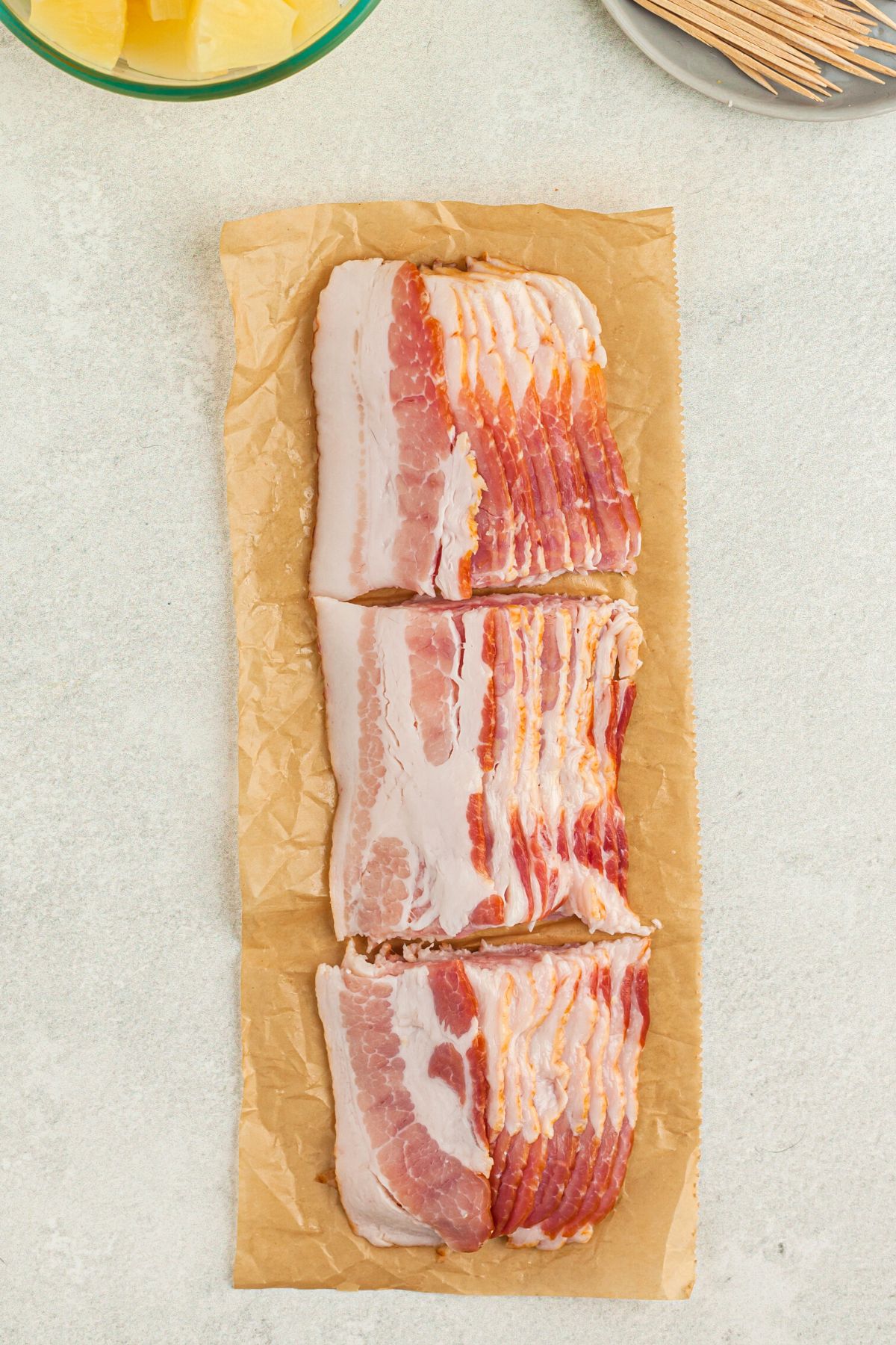 Bacon slices cut into thirds on parchment paper