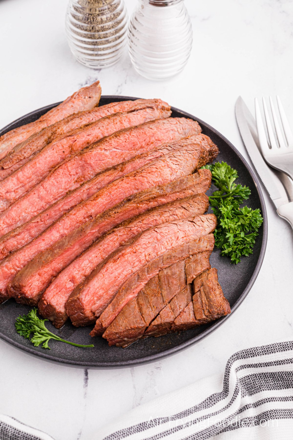 Flank steak air fried, sliced, and served on a platter. 