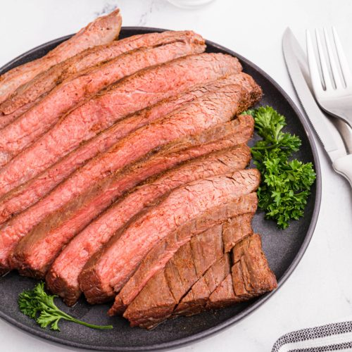 Flank steak sliced and served on a platter.