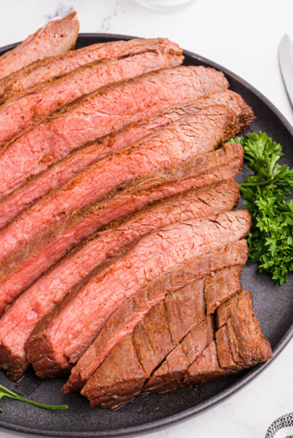 Flank steak sliced and served on a platter.