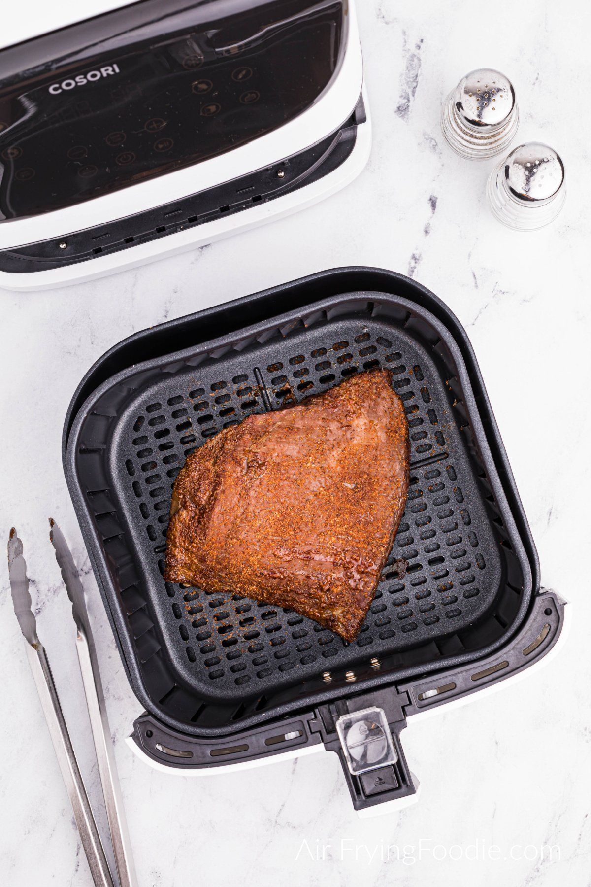 Seasoned and air fried flank steak in the basket of the air fryer.