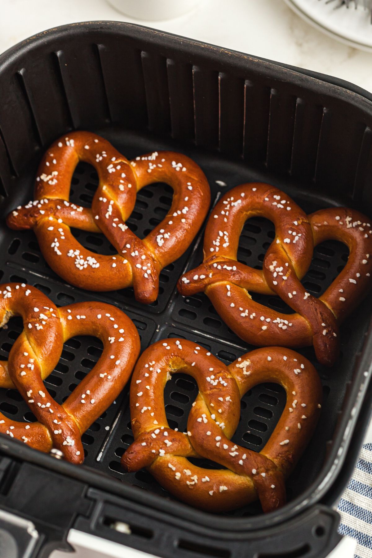 Golden salted pretzels in the air fryer basket after being heated