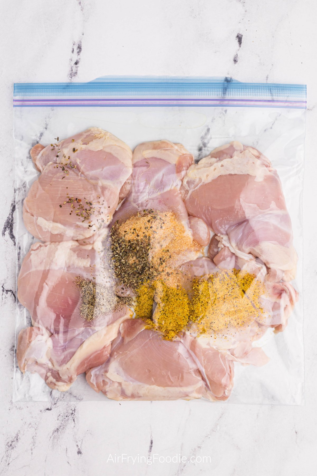 Seasonings and chicken thighs in a sealable plastic bag.