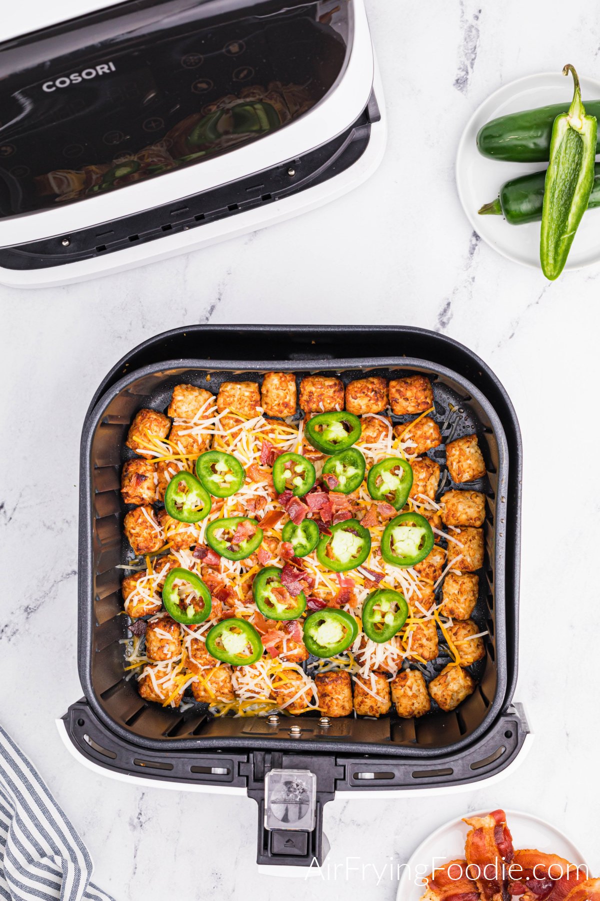 Air fried tater tots topped with cheese, bacon, and jalapeno slices.