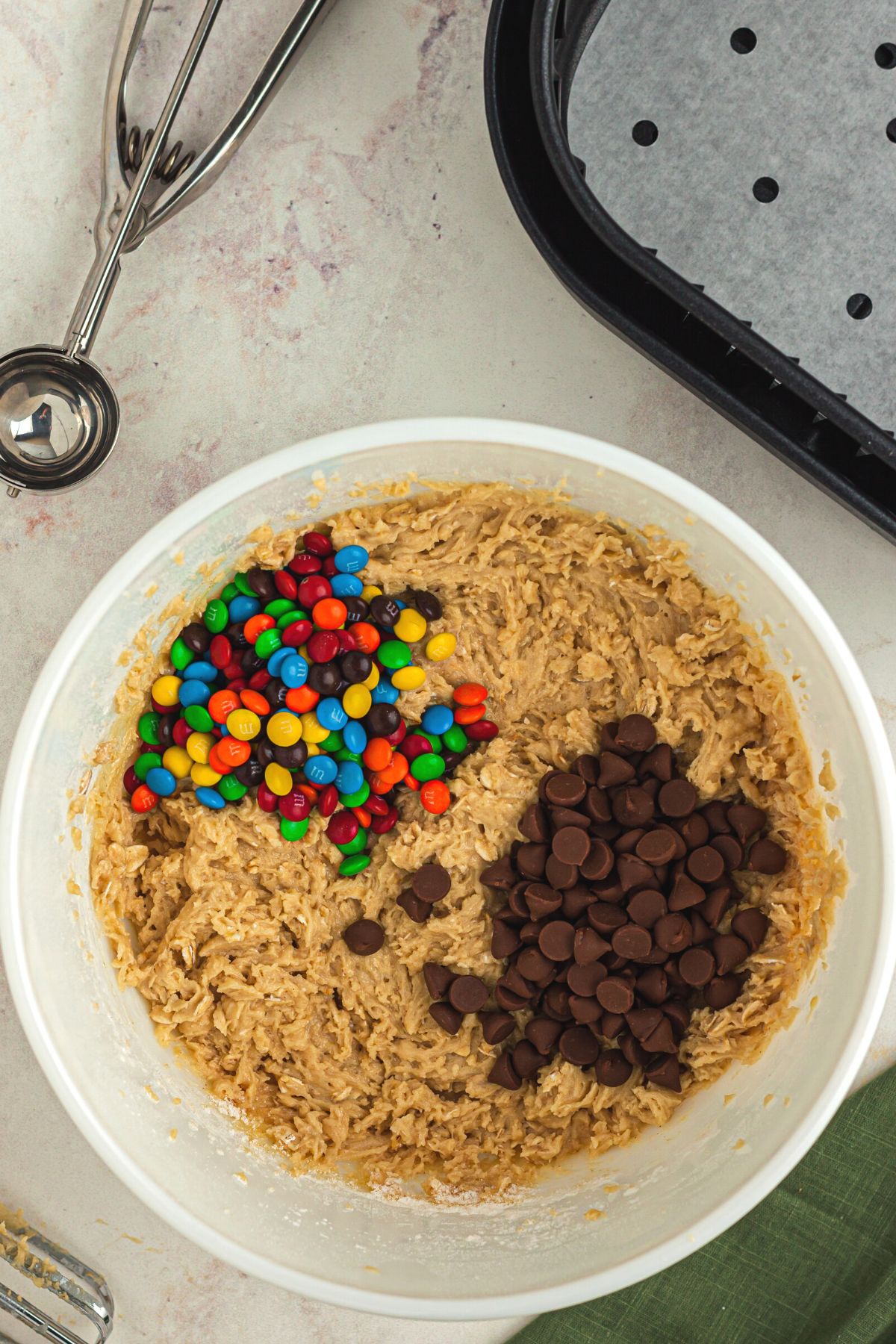 M and ms, chocolate chips in a white bowl with cookie dough