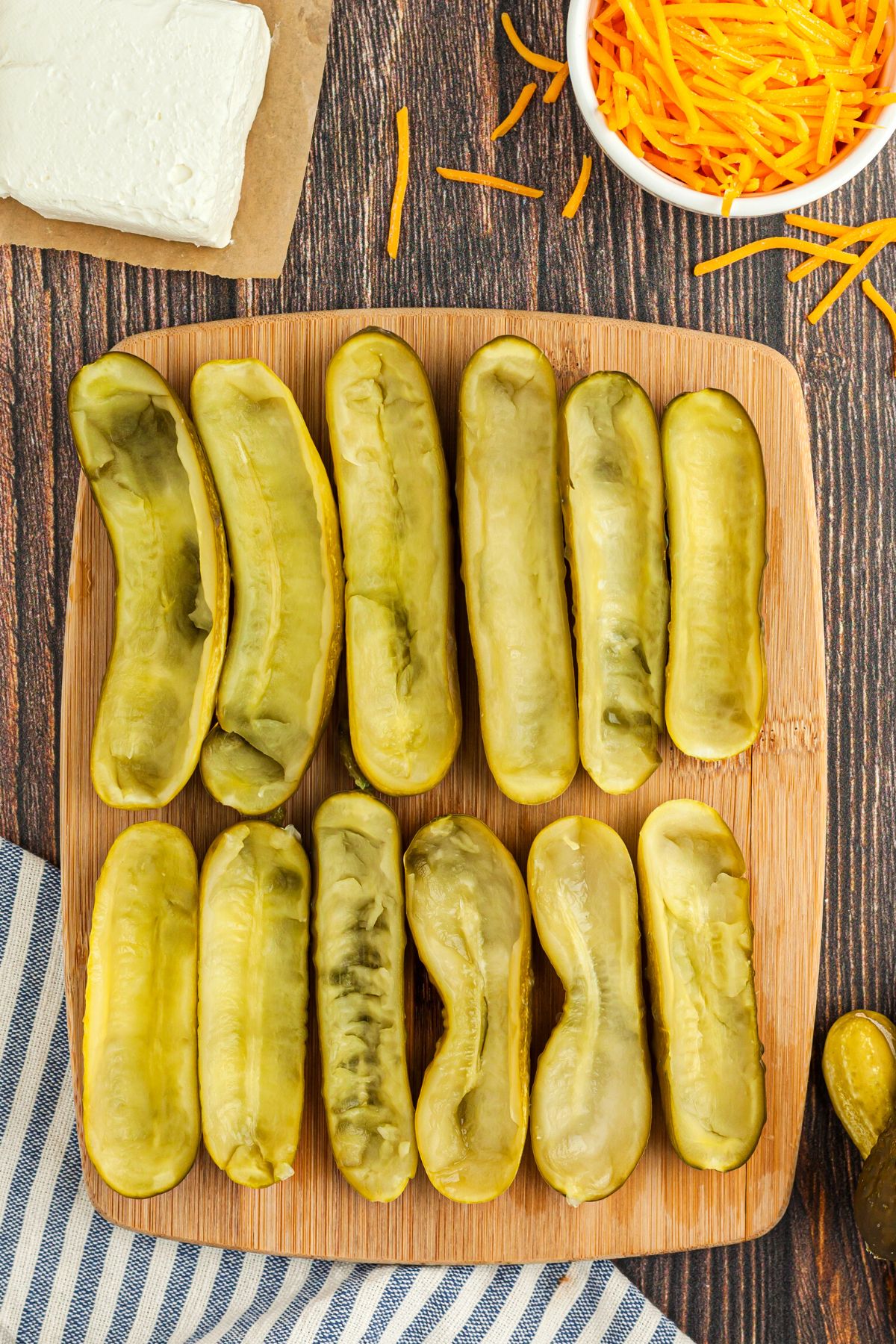 Pickles sliced in half on a cutting board with the middle scooped out