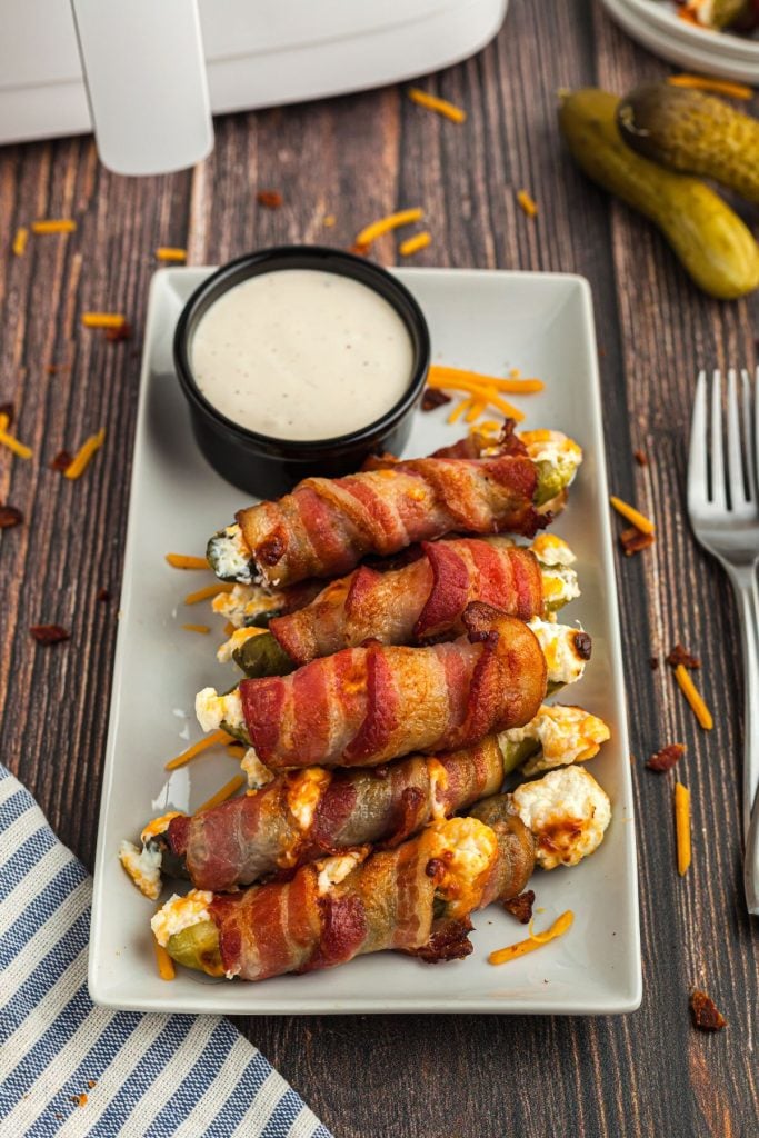 Rectangle plate with bacon wrapped pickles filled with cream cheese