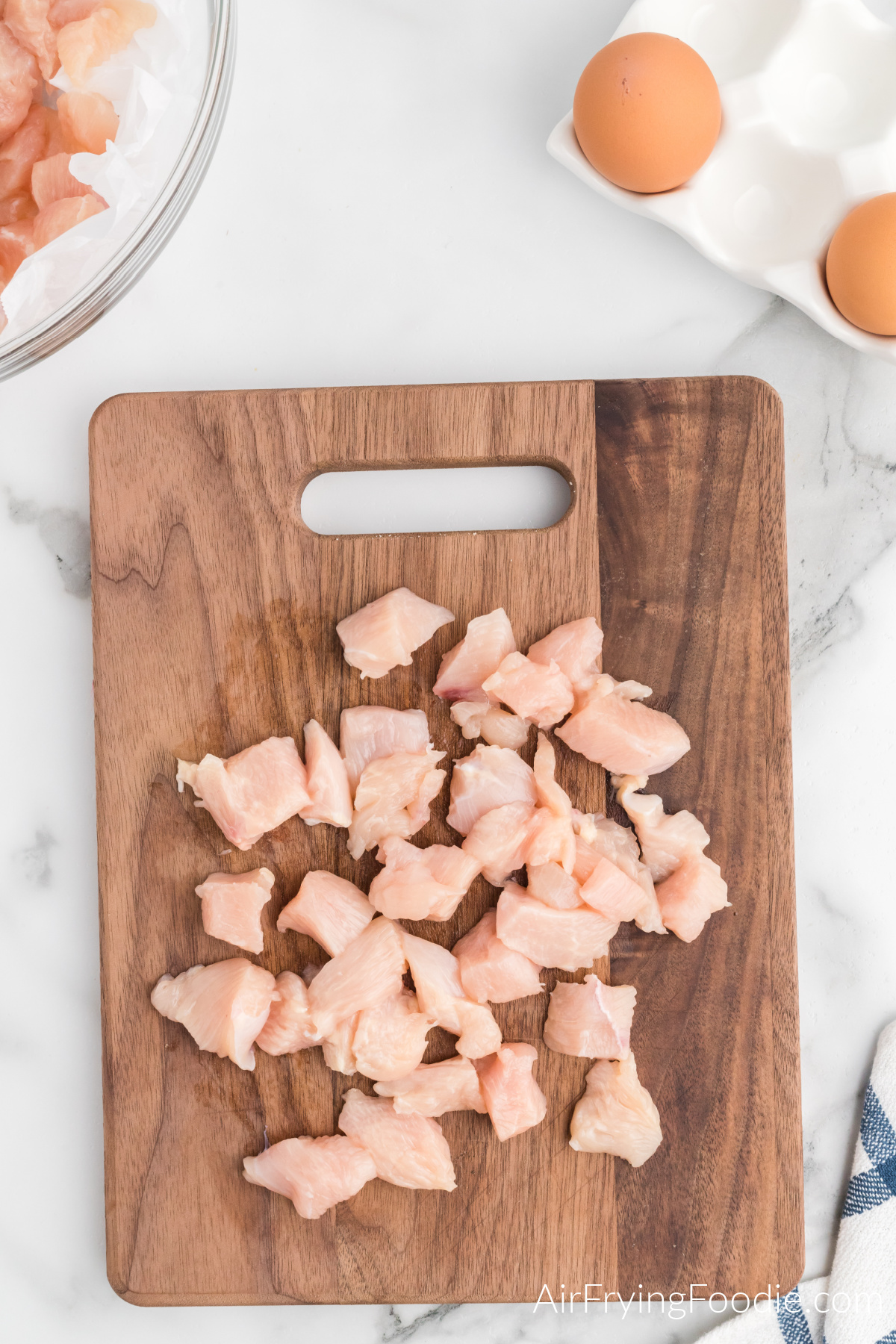 chicken breasts cut into bite sized pieces on a cutting board.