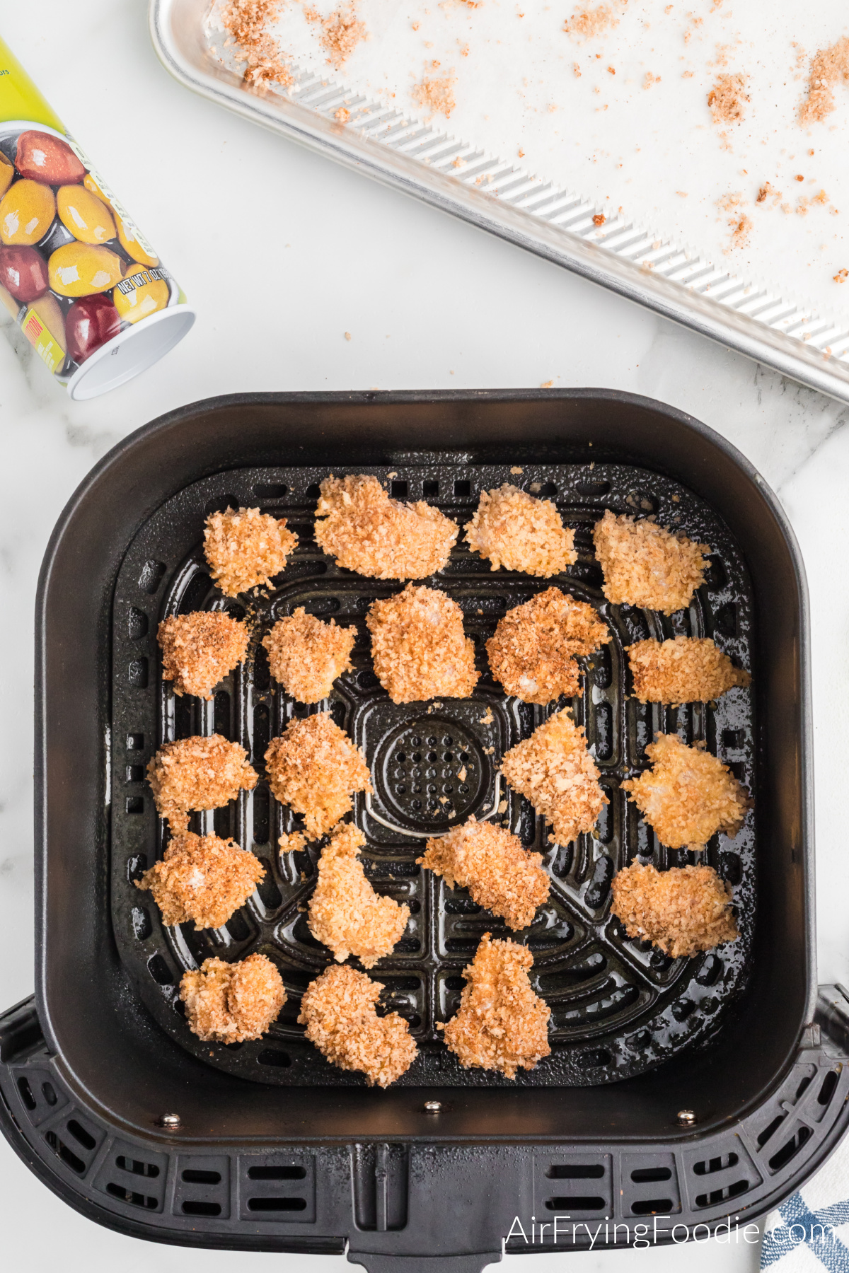 breaded and seasoned popcorn chicken in the basket of the air fryer.
