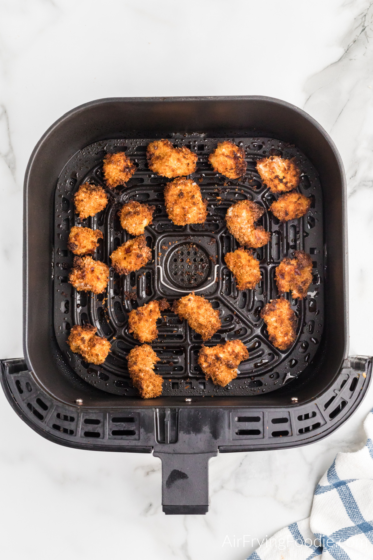 Air fried popcorn chicken in the basket of the air fryer.