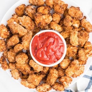 tray of popcorn chicken on a serving plate with a bowl of ketchup for dipping.