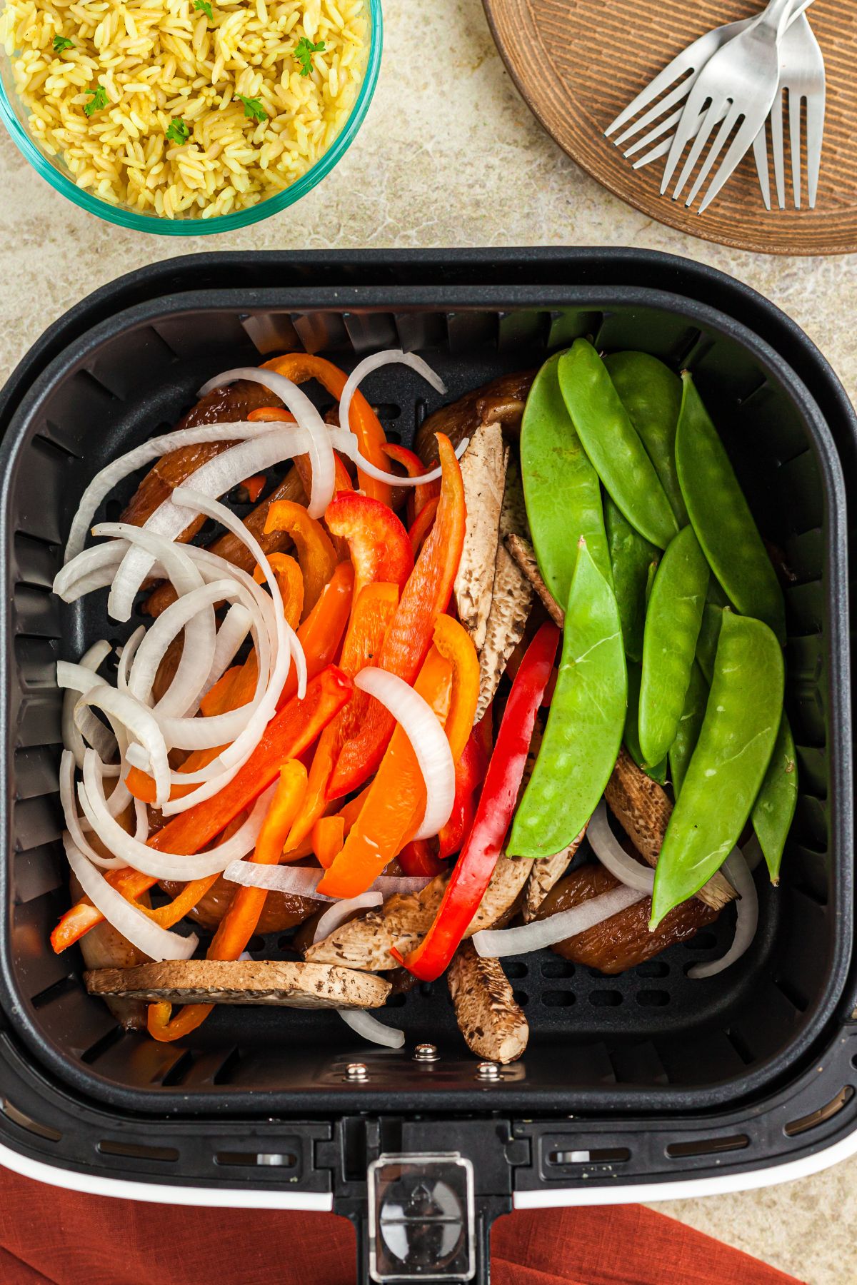 Uncooked vegetables and chicken in the air fryer basket