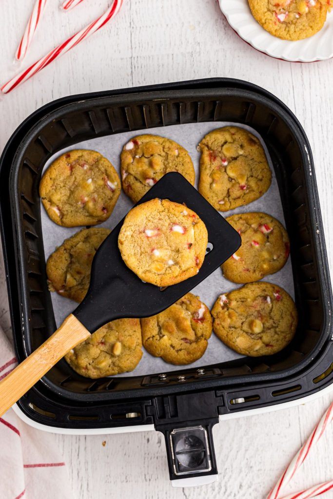 Golden cookie on a black spatula being lifted out of an air fryer basket