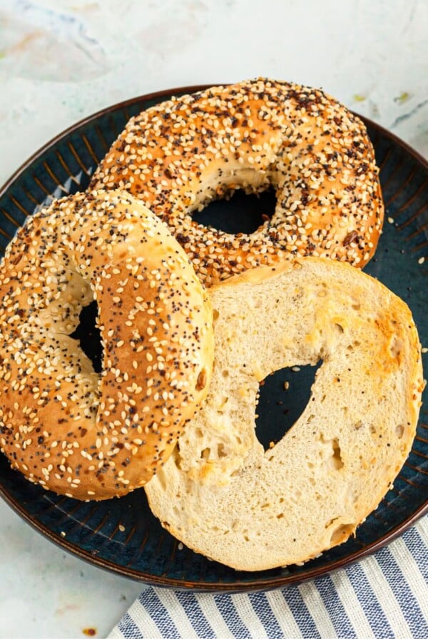 Lightly golden toasted bagels on a blue plate served with cream cheese