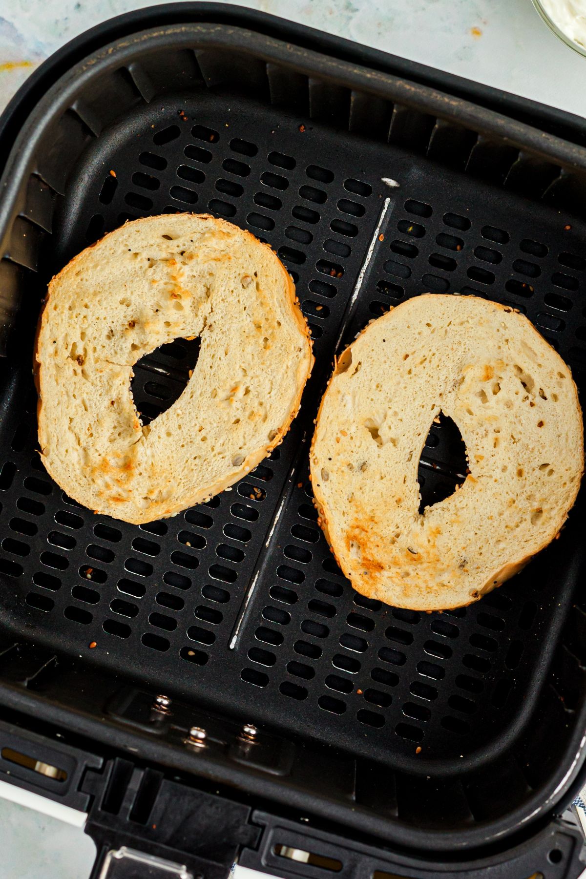 Lightly golden toasted bagels in the air fryer basket