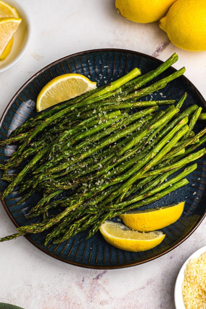 Juicy asparagus topped with a  sprinkle of parmesan cheese and lemon wedges.