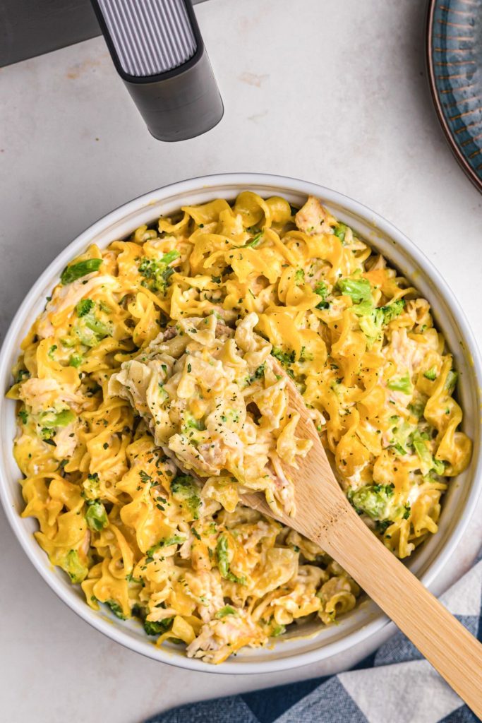 Spoonful of creamy cheesy pasta with chicken in a caserole dish