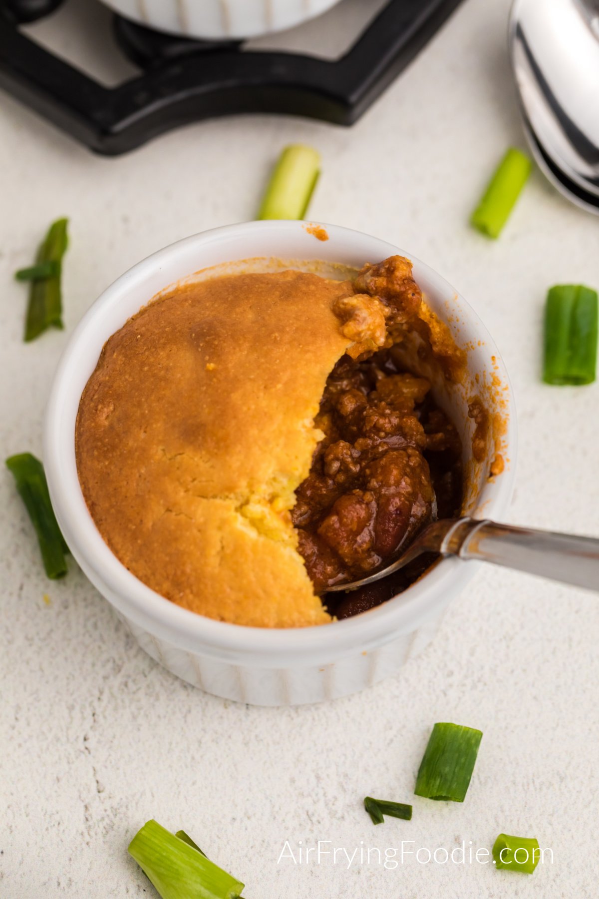 Overhead photo of chili pot pie with a spoon inside.
