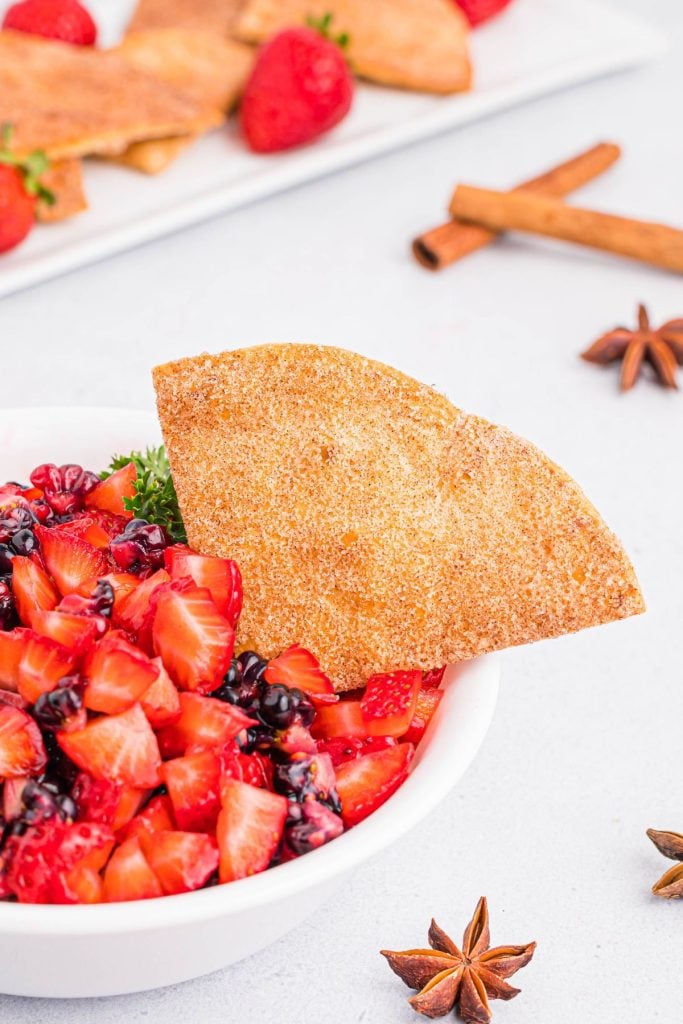 Cinnamon coated tortilla chips in a bowl filled with chopped fruits
