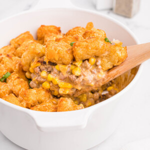 Air fryer cowboy casserole fully cooked with a wooden spoon removing a serving.