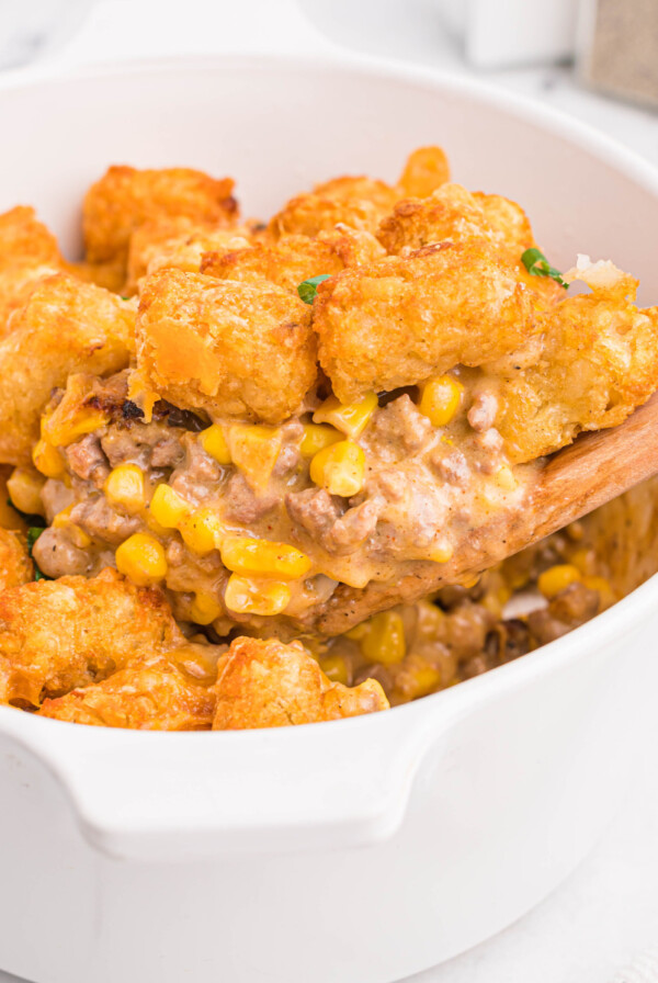 Air fryer cowboy casserole fully cooked with a wooden spoon removing a serving.