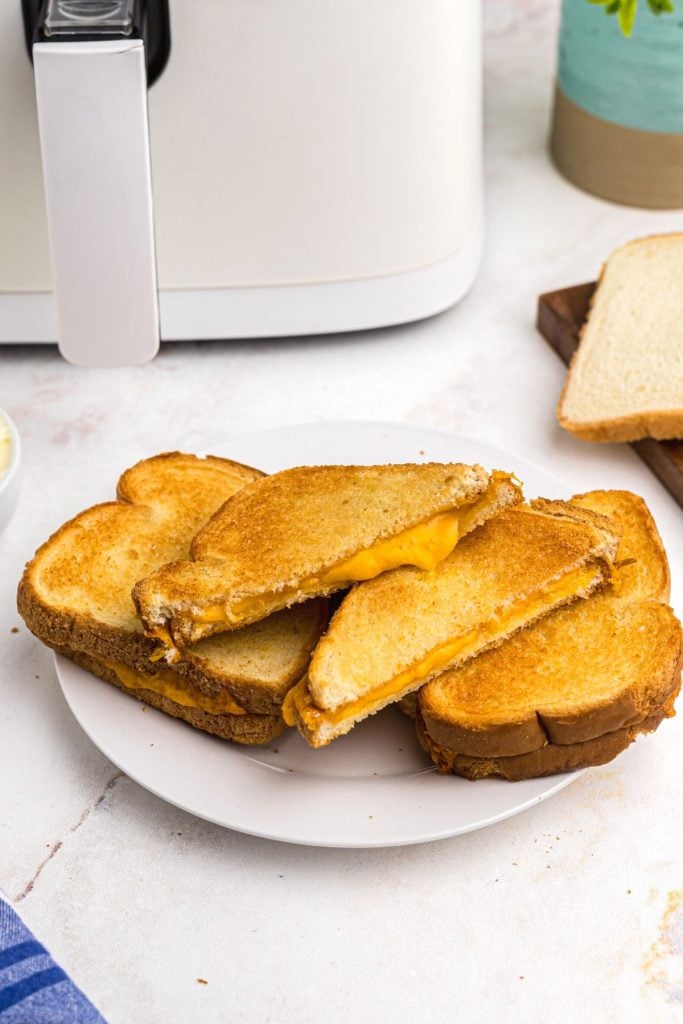 Golden crispy grilled cheese sandwich on a white plate sliced