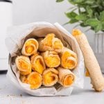 Grilled cheese roll ups cooked in the air fryer and served in a tin container lying on its side.