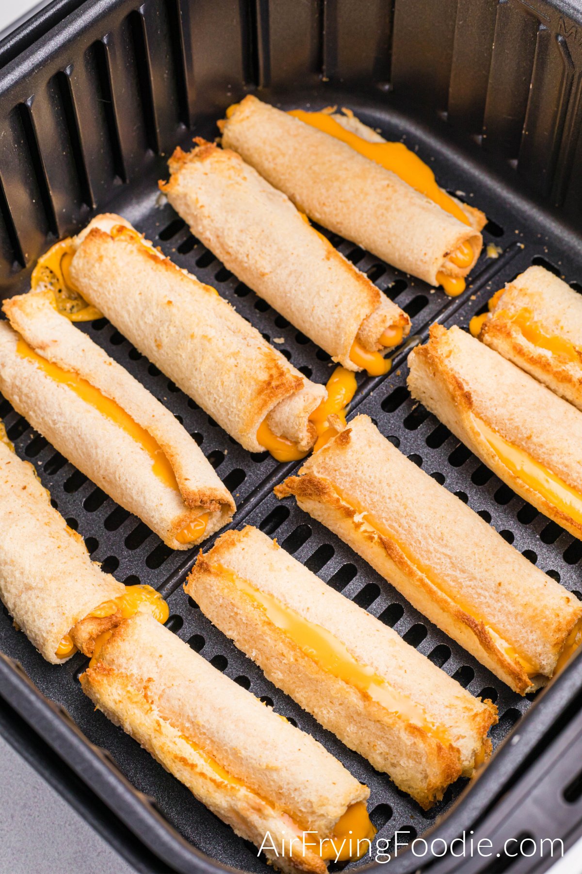 Close-up of fully cooked grilled cheese roll ups in the air fryer basket.