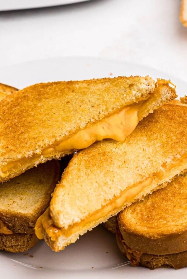 Golden crispy grilled cheese sandwich sliced in half with melty cheese coming out