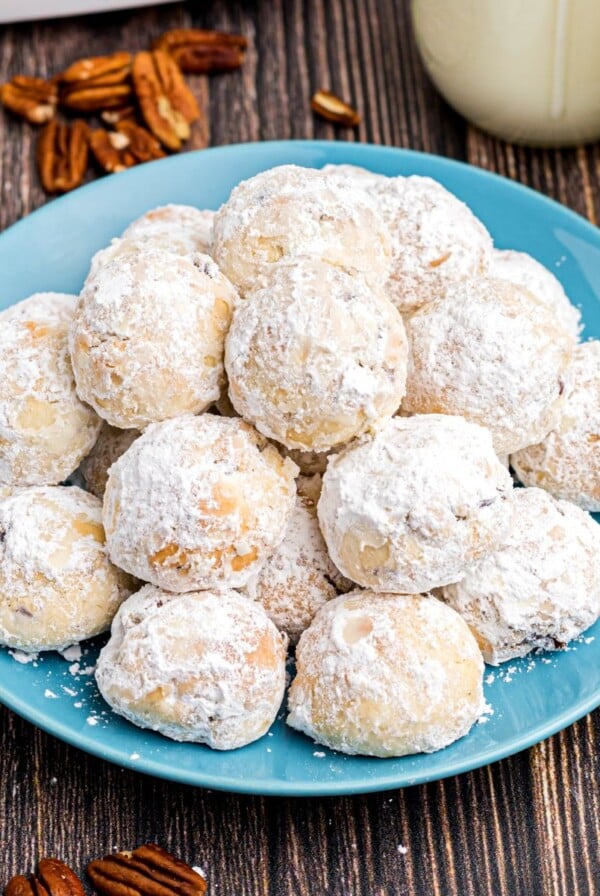 White powdered coated snowball cookies stacked on a blue plate