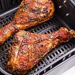 Golden brown crispy turkey legs in the air fryer basket.