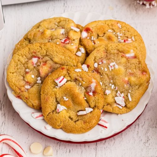 Golden cookies on a white plate with peppermints and white chips scattered on the table