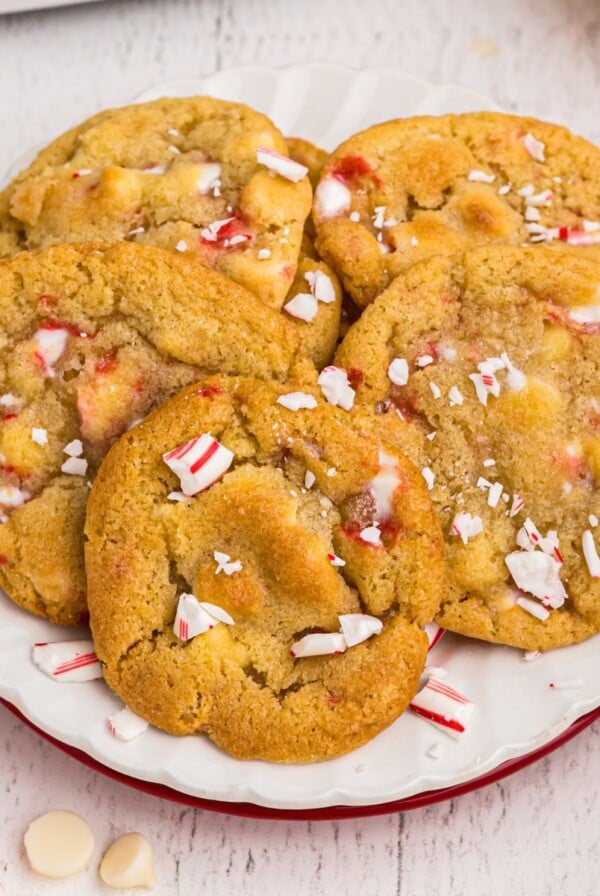 Golden cookies on a white plate with peppermints and white chips scattered on the table