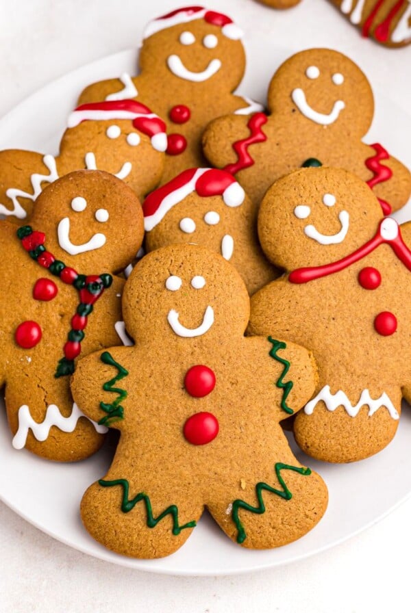 Golden gingerbread cookies on a white plate frosted with red, white, and green frosting