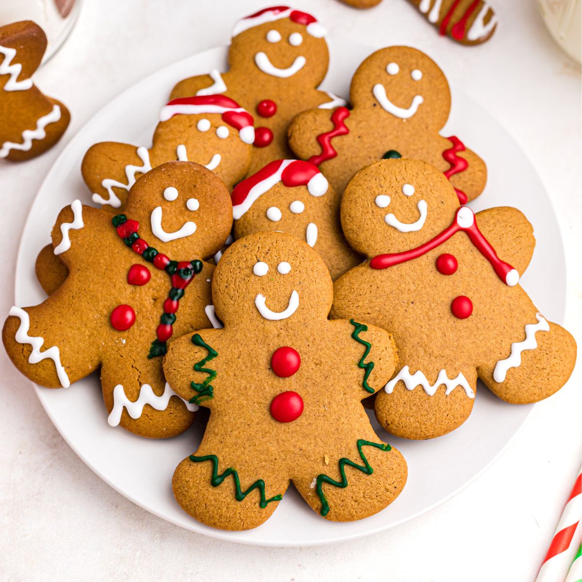 Golden gingerbread cookies on a white plate frosted with red, white, and green frosting
