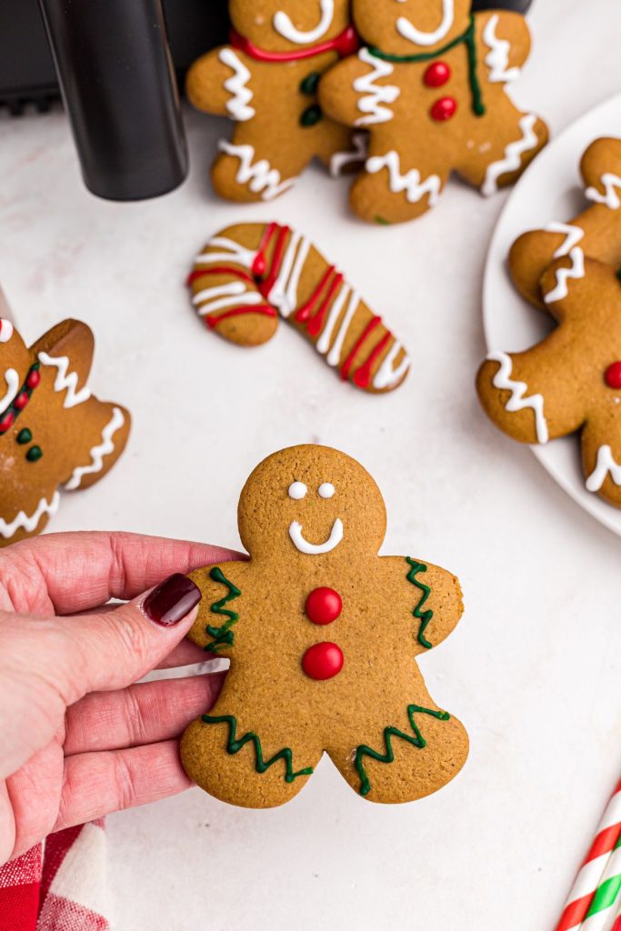 Hand holding golden gingerbread man decorated with frosting.