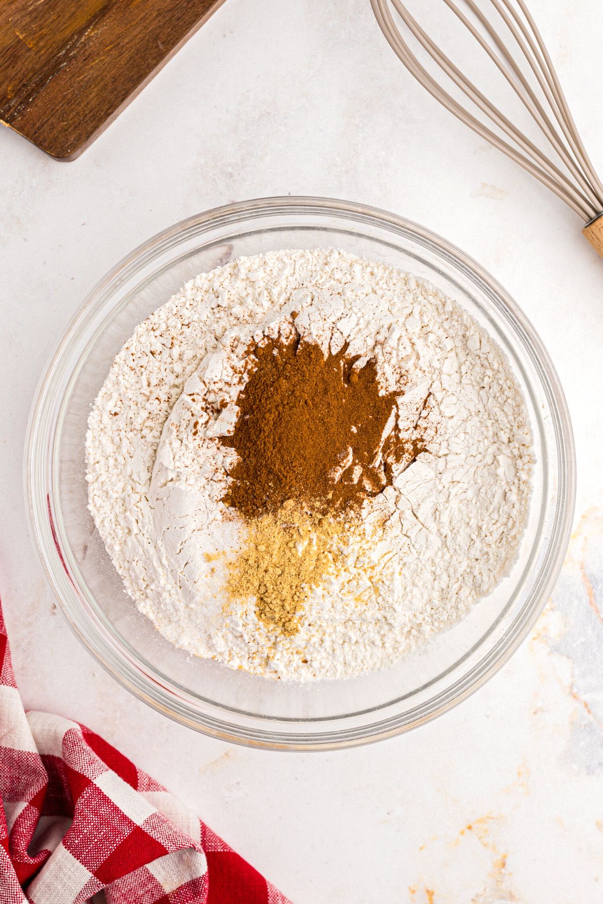 flour, cinnamon, and other seasonings being mixed in a clear bowl