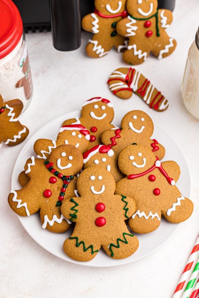 Golden gingerbread men on a white plate in front of an air fryer