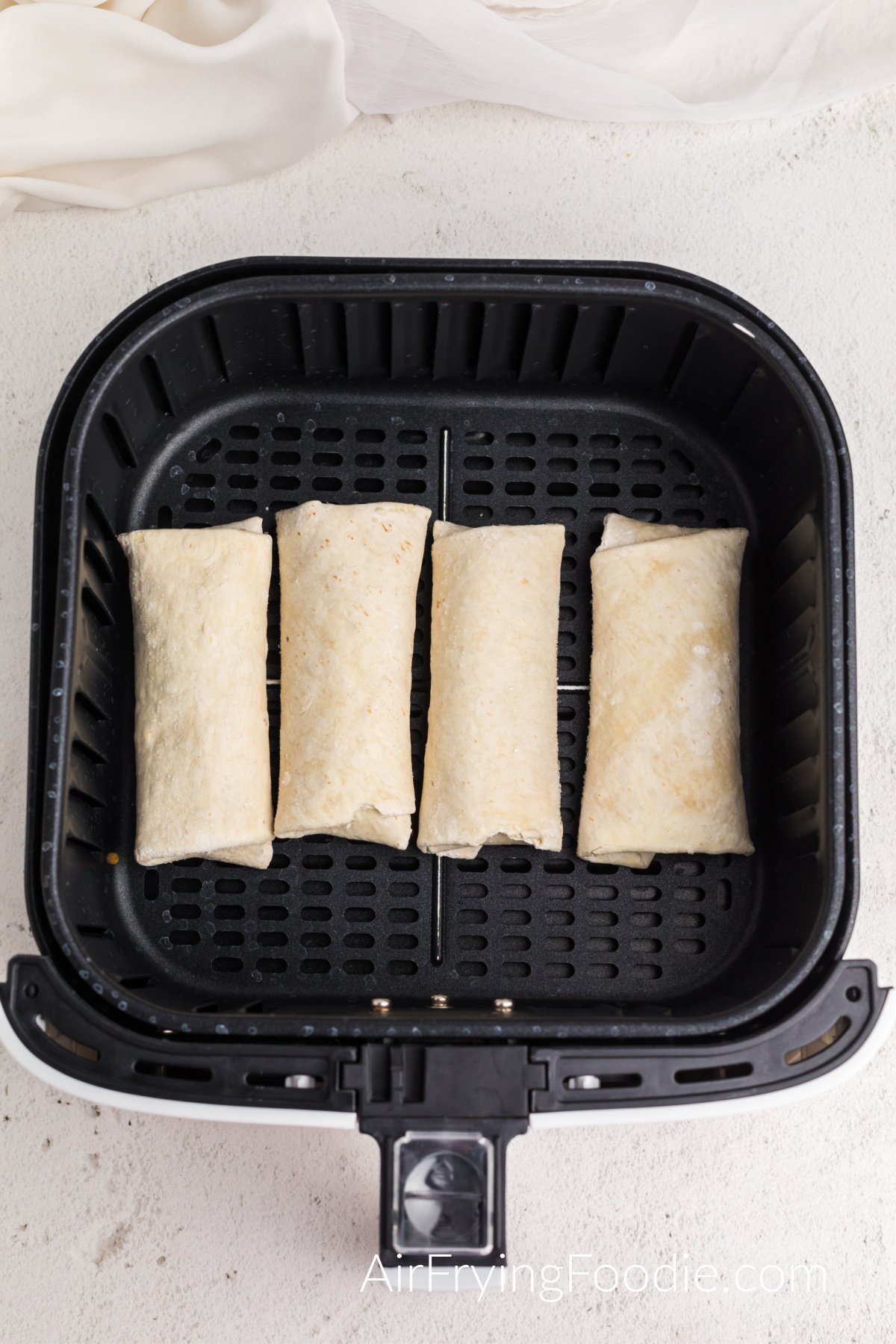 frozen burritos in a single layer in the basket of the air fryer.