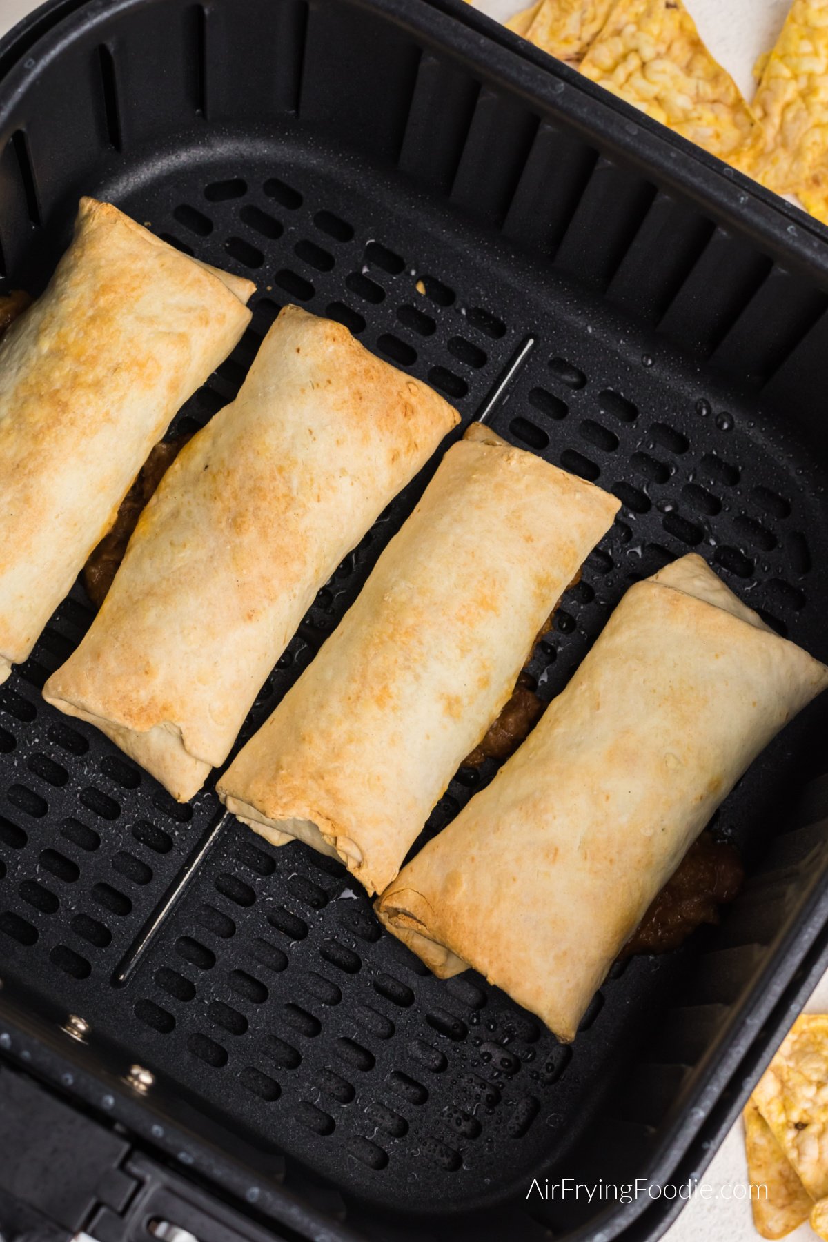 Beef and bean burritos air fried in the basket of the air fryer.