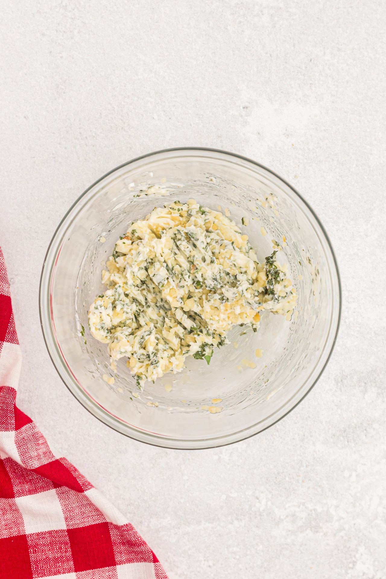 Butter, garlic and seasoning mixed in a clear glass bowl. 