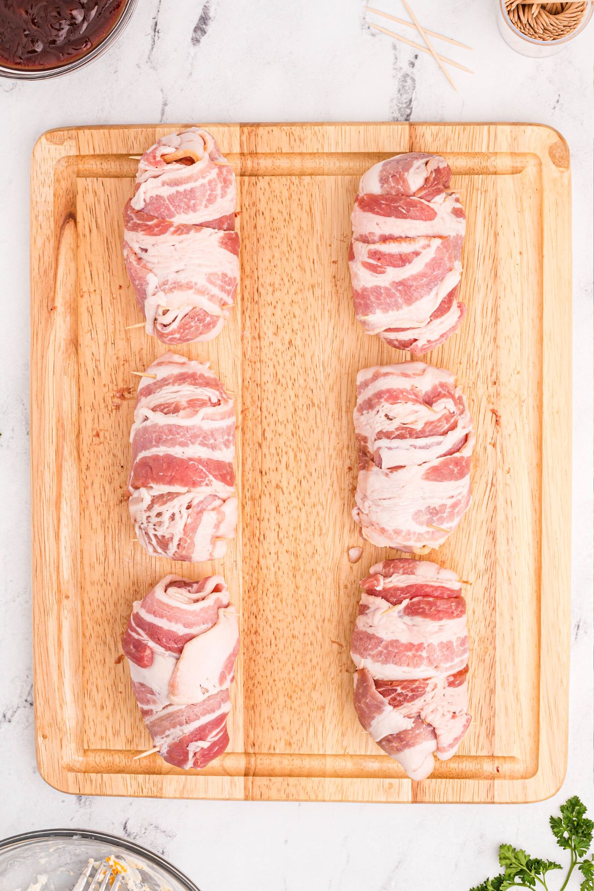 Sausage and bacon wrapped poppers on a cutting board
