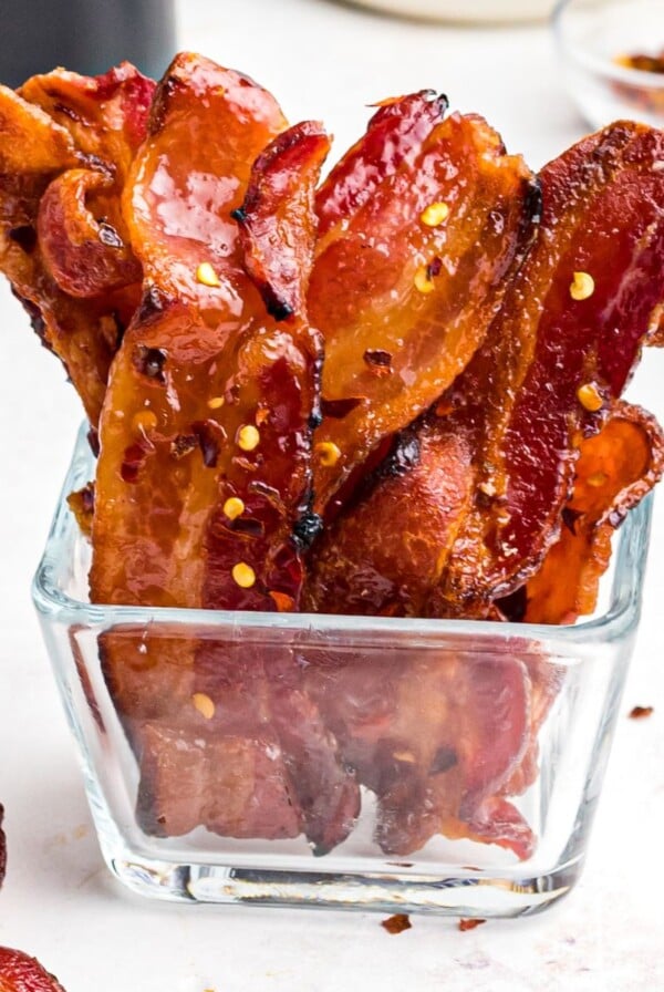 Crispy juicy candied bacon in a clear glass jar.