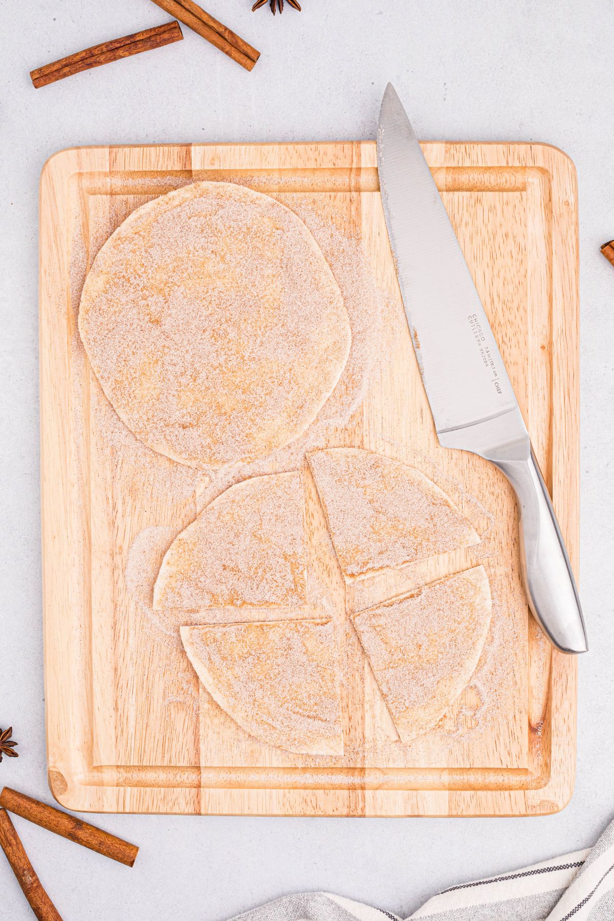 Sugar and cinnamon coating flour tortillas and then cut into triangles on a cutting board