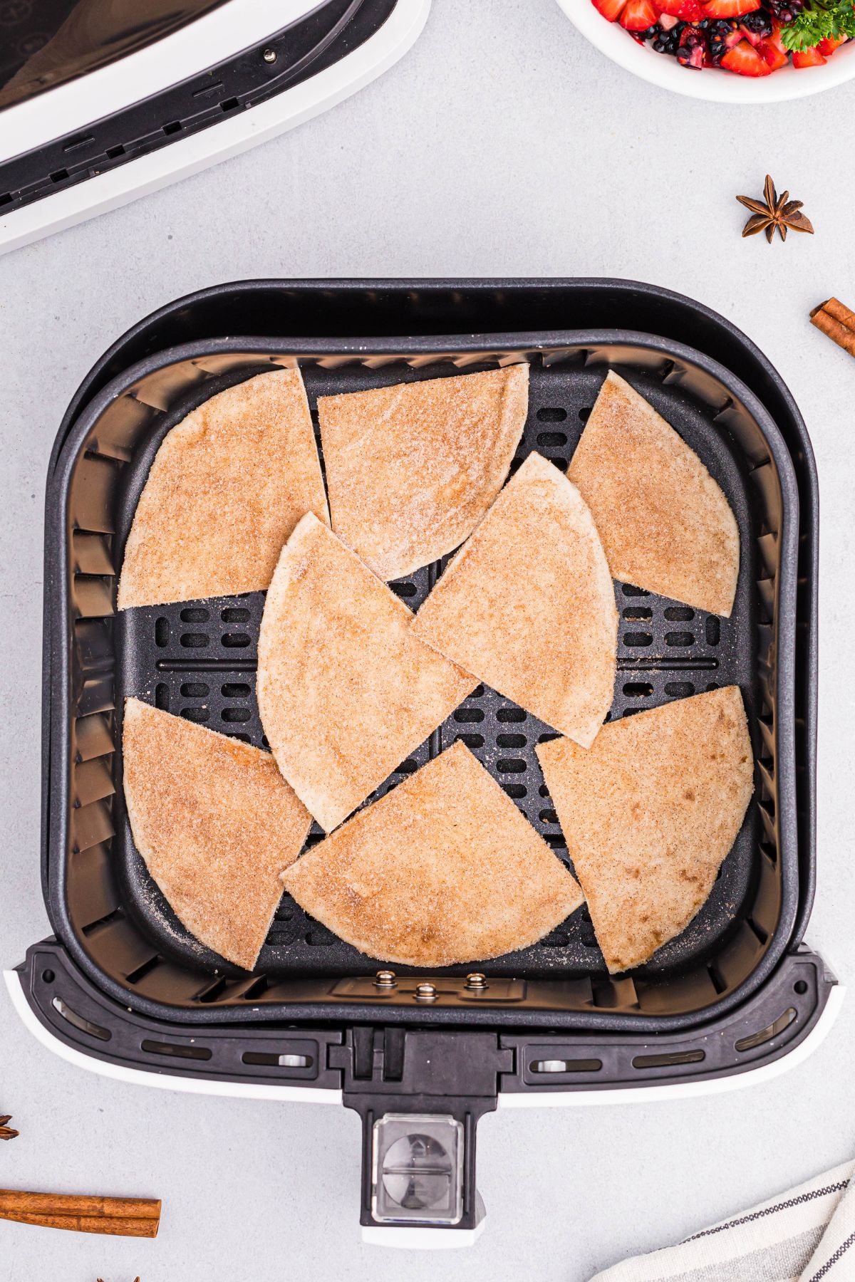 Flour tortilla coated in sugar and cinnamon cut into slices in the air fryer basket