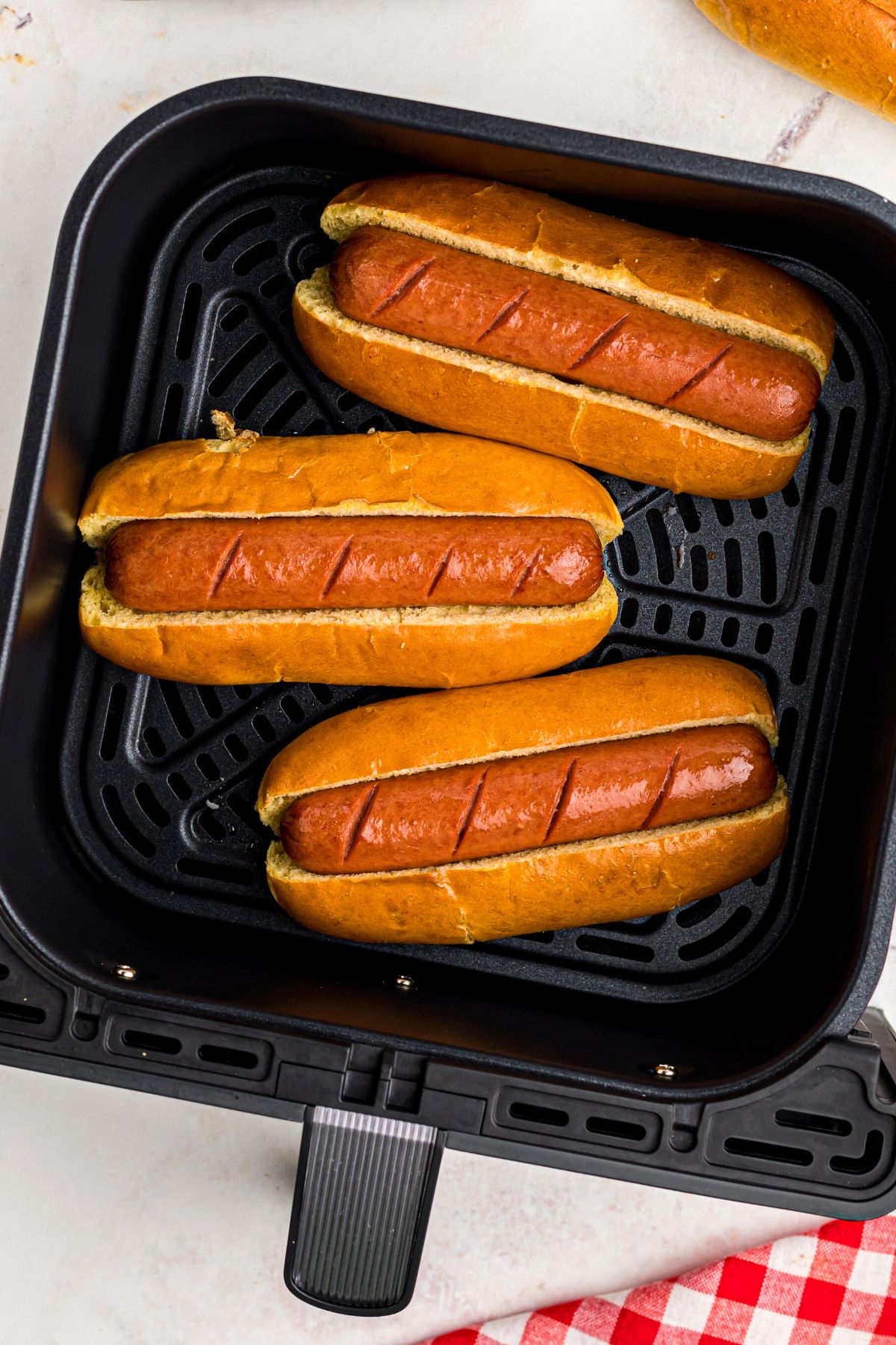 Air fried hot dogs in toasted buns in the air fryer basket